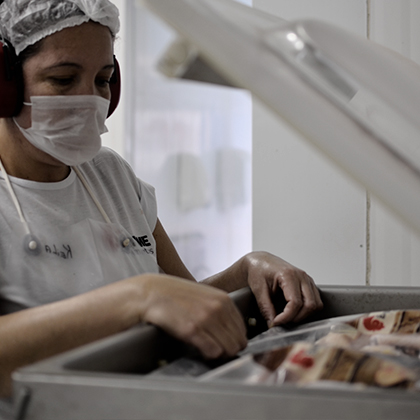 Colaboradora embalando frango caipira na seladora